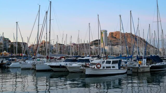 ALICANTE, SPAIN - APRIL 2023: Timelapse of boats in port. Mountain Benacantil in the background
