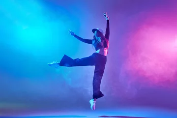 Foto auf Acrylglas Tanzschule a girl in dark clothes dances on a neon background in smoke, modern dance