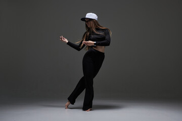 a girl in dark clothes dances and jumps on a dark background background modern dance