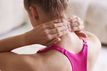 girl in bright sportswear exercising for the neck at home, pain in the neck