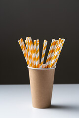 Disposable cardboard biodegradable cup on a white table with a straw.