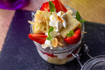 Dessert Eton mess with merengue, berries and whipped cream, served in glass jar on table with empty chalkboard