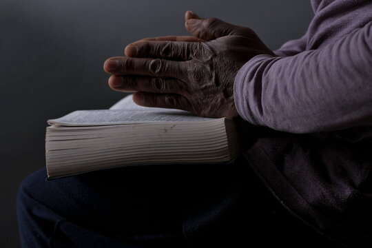 man praying with bible with black background with people stock photo