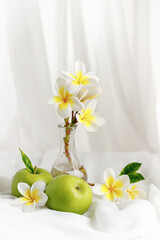 Green apples and white-yellow frangipani flowers. Rosh hashanah concept