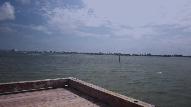 Looking West Time Lapse near the fishing pier at Jungle Prada de Narvaez Park in St. Petersburg, FL. Sunny day wide angle view blue sky with white clouds. Boats in background.
