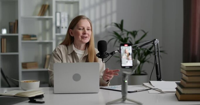 Beautiful woman online podcast host recording video in front of the smartphone.