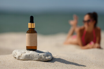 Dropper bottle on the beach. Concept of natural ingredient tanning oil.