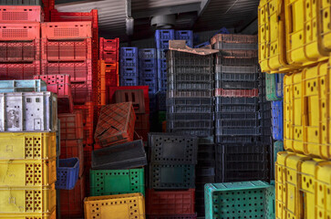 Stacked old and used plastic crates or boxes for transporting food products, to be recycled for further utilization. Selective focus.