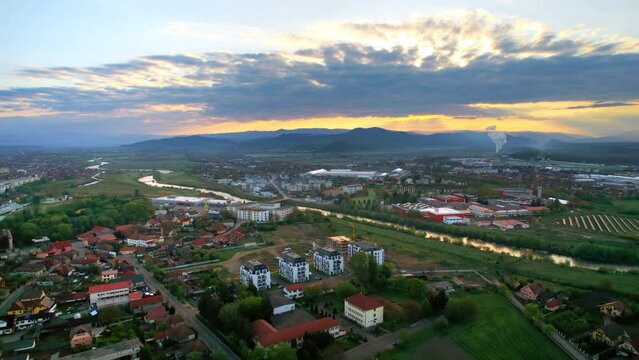 Aerial drone view of Oradea at sunset, Romania. View of a residential district with multiple buildings, Crisul Repede river and hills in the distance