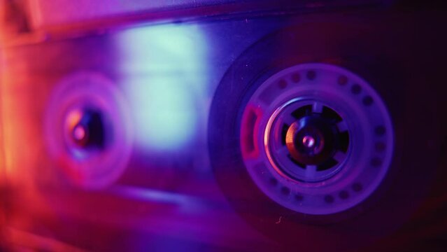 Vintage cassette recorder roller. Audio reel tape is rotating at an old school professional player. Retro night club disco party or synthwave aesthetics concept. DJ remix or mixtape purple background