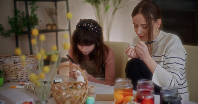 Mother and daughter are painting Easter eggs for Easter Holidays