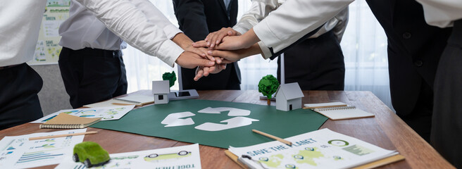 Group of business people put hand stack showing synergy of corporate cooperation on environmental...