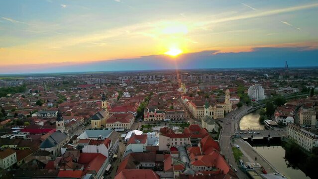 Areal drone view of the Unirii Square in Oradea downtown at sunset, Romania. King Ferdinand I statue, Saint Ladislaus Church, Town Hall and other historical buildings, walking people