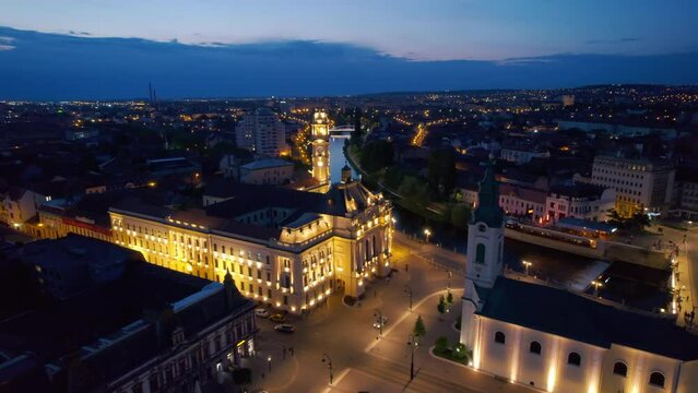 Areal drone view of the Unirii Square in Oradea downtown at night, Romania. Saint Ladislaus Church and Town Hall, illumination
