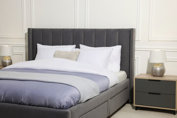 Comfortable bed between bedside tables with lamps at home. Interior design