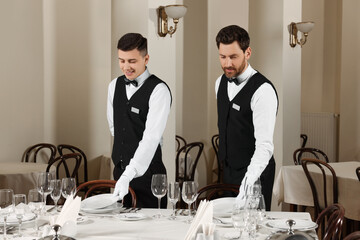 Men setting table in restaurant. Professional butler courses
