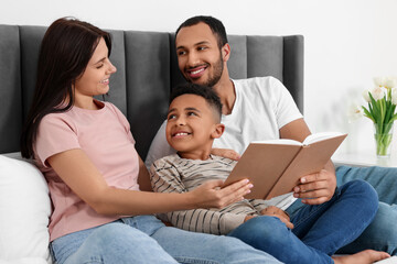 Fototapeta premium Happy international family reading book on bed