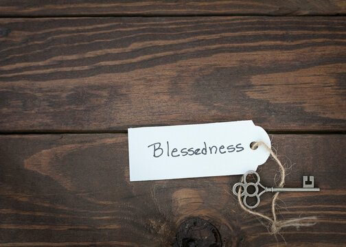 The key of blessedness concept isolate. Silver key with a label on wood table.