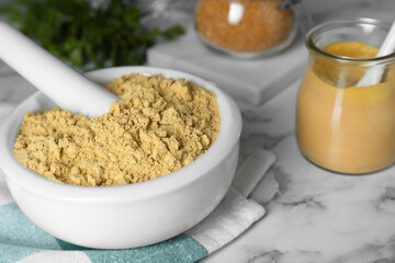 Mortar with aromatic mustard powder on white marble table, closeup