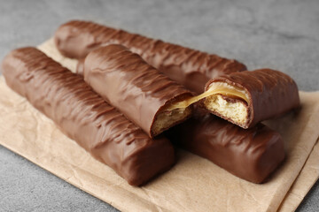 Sweet tasty chocolate bars with caramel on grey table, closeup