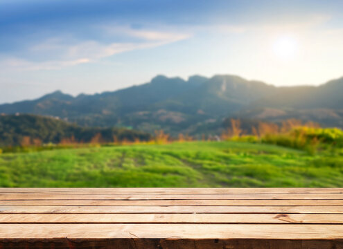 Fototapeta Wooden table top on blur mountain and grass field. Fresh and Relax concept. For montage product display or design key visual layout. View of copy space.