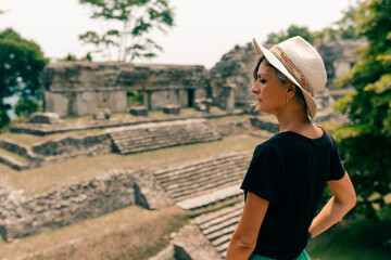 Hiker wonam with a hat looking at ancient Mayan ruins