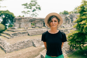 Obraz premium Hiker wonam with a hat looking at ancient Mayan ruins