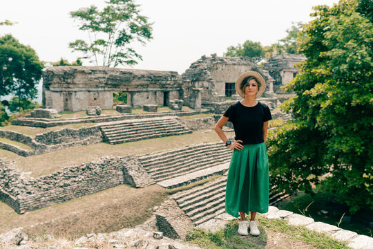 Hiker wonam with a hat looking at ancient Mayan ruins