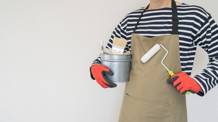DIYイメージ｜塗装道具を持つエプロン姿の男性