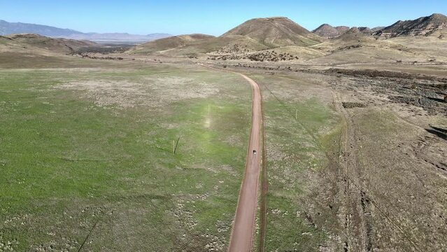 Drone shot of car driving on dirt road in Willcox, Arizona, wide following aerial shot