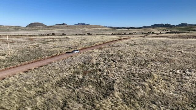 Drone shot of car driving on dirt road in Willcox, Arizona, rising aerial shot