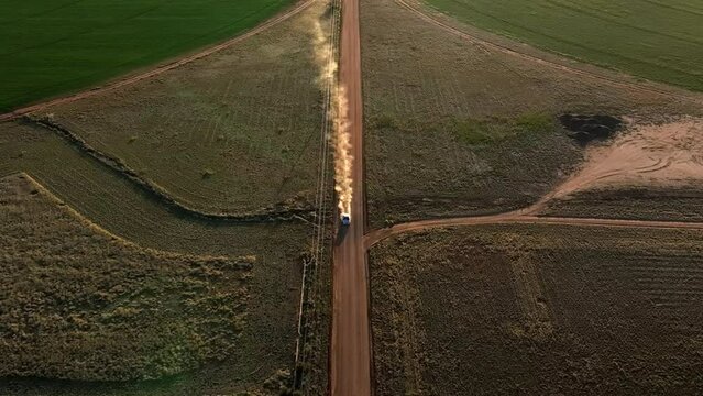 Aerial shot of car driving on dirt road in near pivots with green farm growth in Willcox, Arizona, wide downward angle drone shot