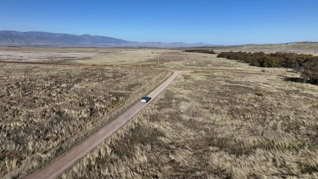 Drone shot of car driving on dirt road in Willcox, Arizona, wide rising aerial shot