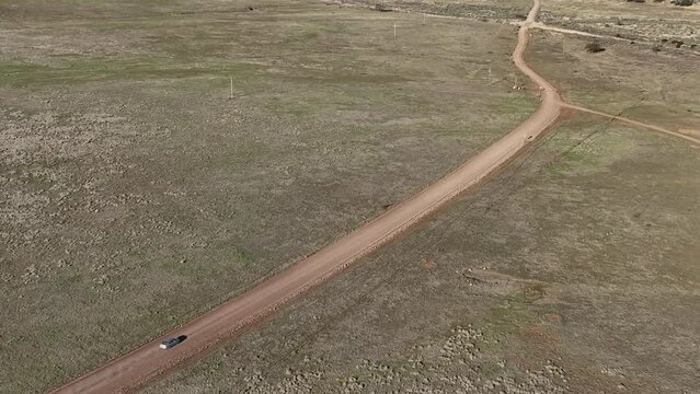 Drone shot of car driving on dirt road in Willcox, Arizona, wide downward angle aerial shot