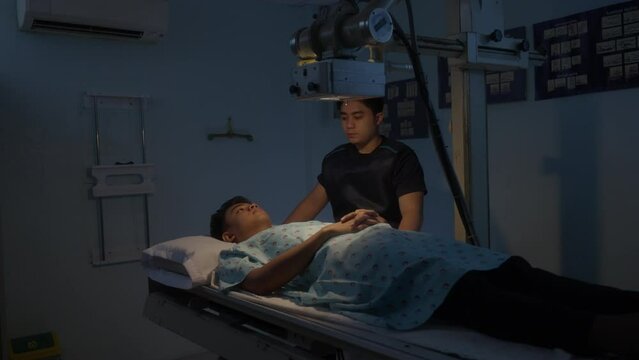 Radiologist Taking An X-ray Of A Young Man Patient Lying On The Table Machine. Static Shot