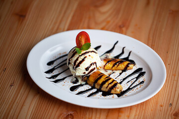 Pisang Bakar Coklat or Grilled Banana Chocolate serve with chocolate and ice cream and strawberry graters on white plate.