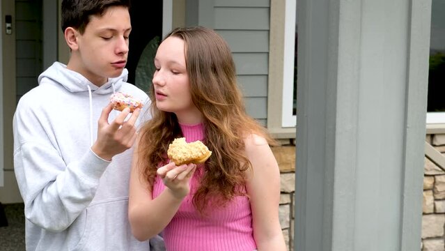 children tasting fingers on porch girl biting from boy's hands delicious dessert wide open mouth friends having fun chatting kindness share with friend