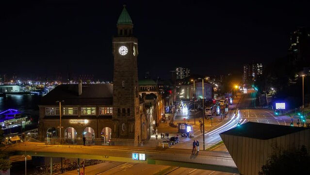 Timelapse video of Hamburg downtown traffic on a clear autumn night, prominently featuring a clock tower with roman numerals and bustling streets under a starry sky.