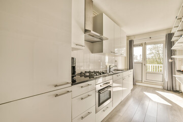 a kitchen with white cupboards and appliances on the counter top in front of the oven, looking into...
