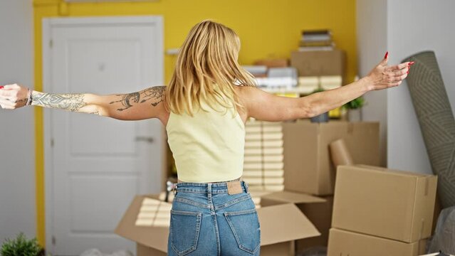 Young blonde woman smiling confident turning by herself with arms open at new home