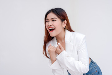 An overjoyed and laughing young woman leaning forward with raised fists in celebration.Isolated on a white background.