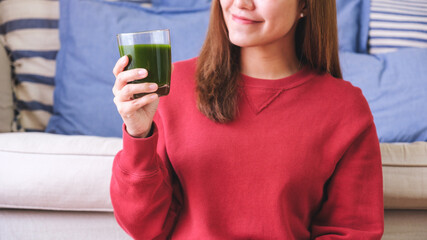 Closeup image of a young woman drinking kale smoothies