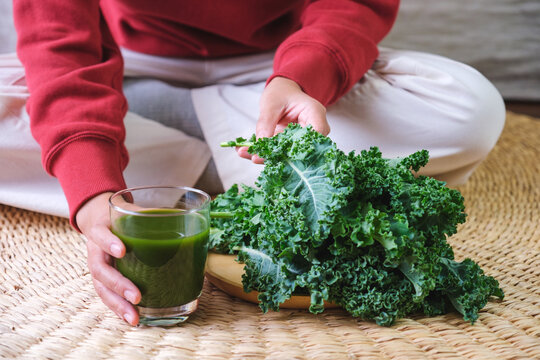 Closeup image of a young woman holding kale leaves and kale smoothies