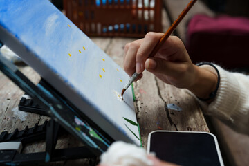 Close-up stretched white cloth on wooden frame, hand holding, pointy, white brush at brush, in...