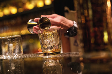 Bartender pours a whiskey into a glass at the bar counter