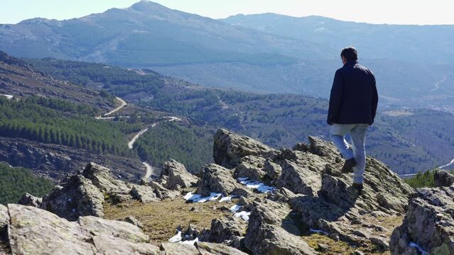 Man with his back climbed on some rocks while contemplating the mountain landscape in the Sierra del Rincon, Madrid