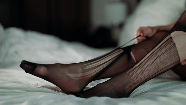 Close-up of slender female feet in pantyhose, she is upset and tearing an item of clothing on herself