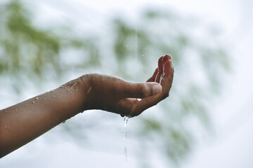 The hand of a boy washing his hands with water, or catching falling water with both palms.