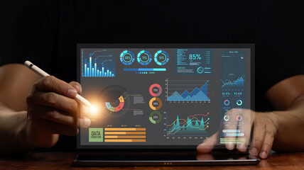 Businessman using tablet to work on digital marketing analytics and data management. business strategy concept Graphs and digital marketing data displayed on virtual screens and business management.