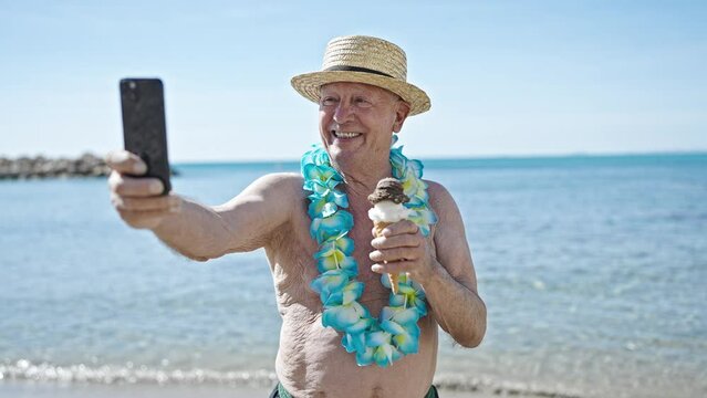 Senior grey-haired man tourist holding ice cream make selfie by smartphone at seaside
